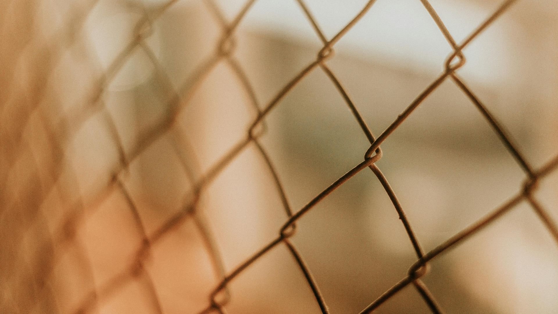 Close-up of rusty chain-link fence with blurred background